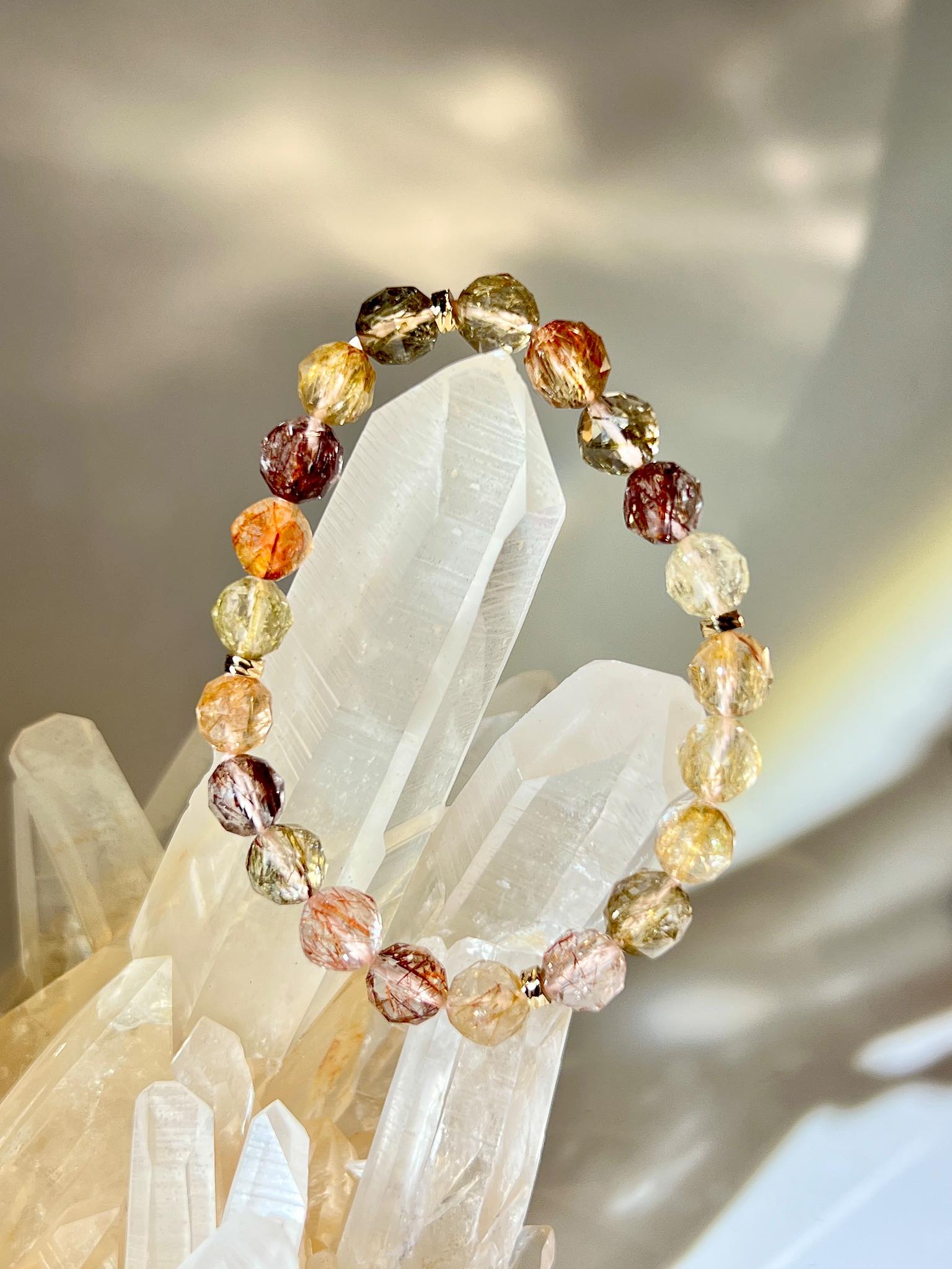 多色天然髮晶手串擺放於白水晶柱上，展示晶體紋理與光澤。