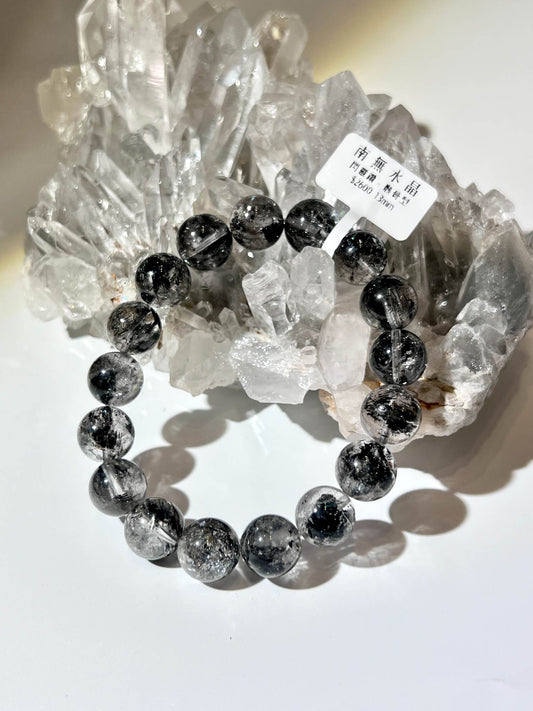 黑閃靈鑽手鍊置於白水晶簇上，展現高折射亮澤與酷黑奢華質感。