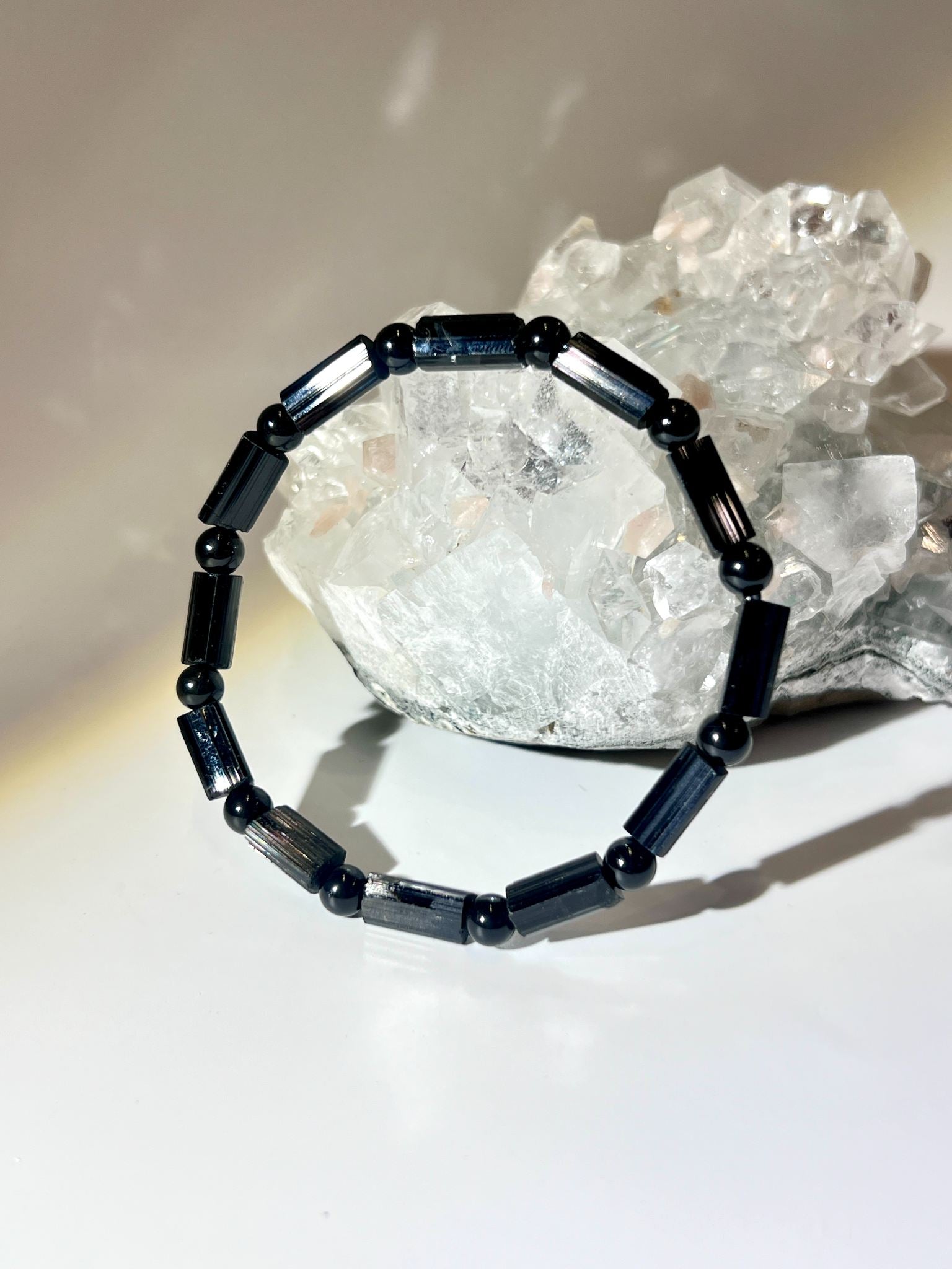 天然莫桑比克黑電氣石手鍊（Black Tourmaline Schorl）放置於白水晶簇前