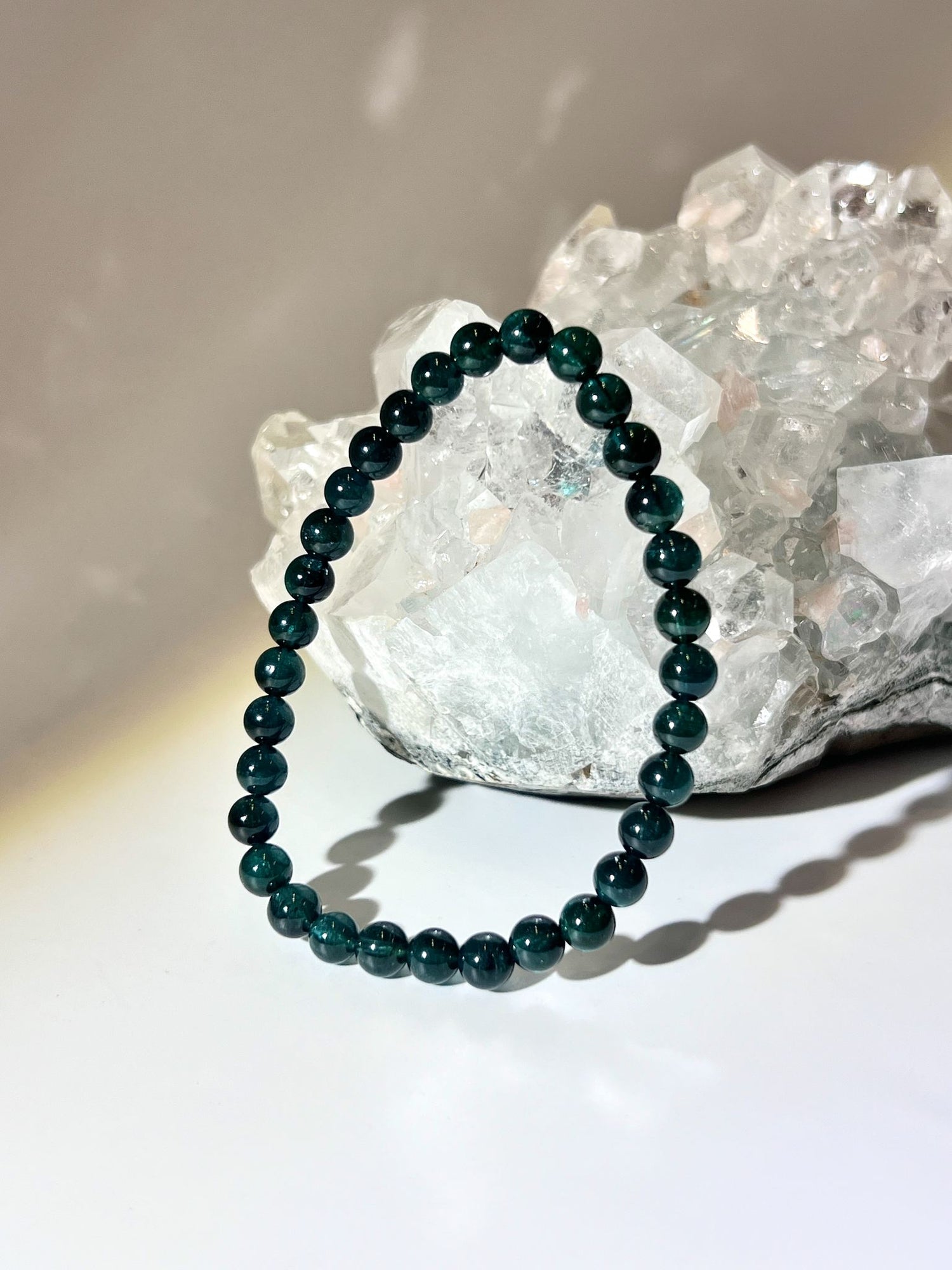天然藍碧璽圓珠手鍊（Indicolite Blue Tourmaline）放置於通透的白水晶簇前