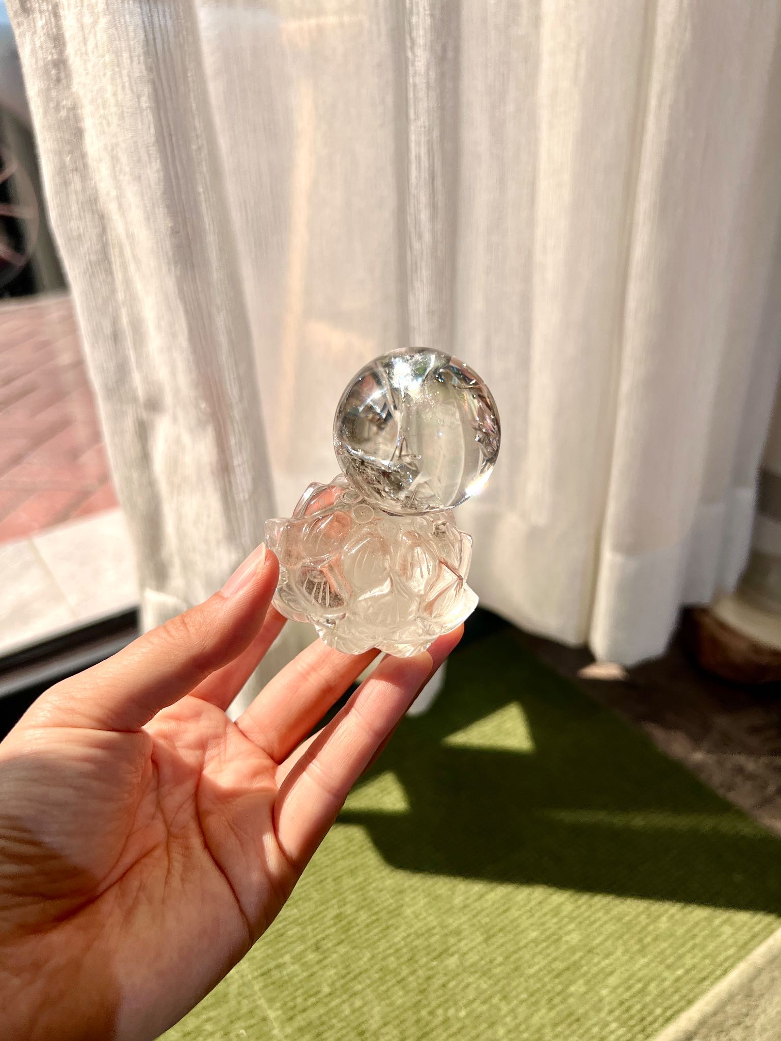 Close-up of lotus-carved quartz base supporting a clear quartz sphere