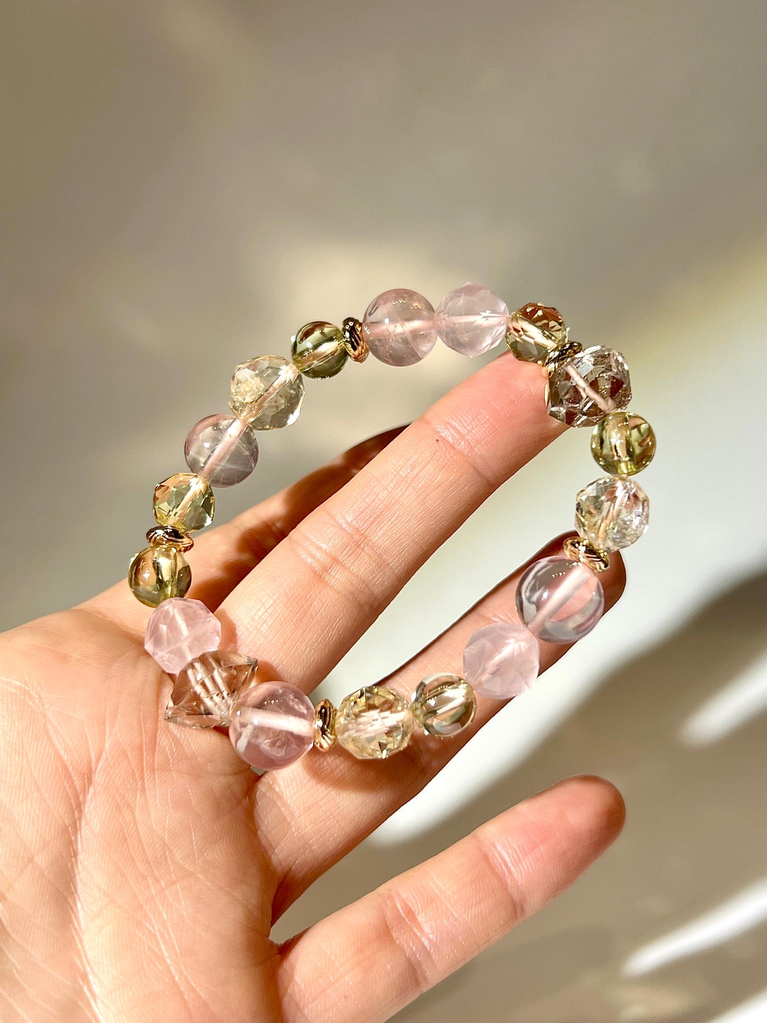 粉晶與黃金色水龍珠的近拍手鏈細節，展現透亮與光影層次。
