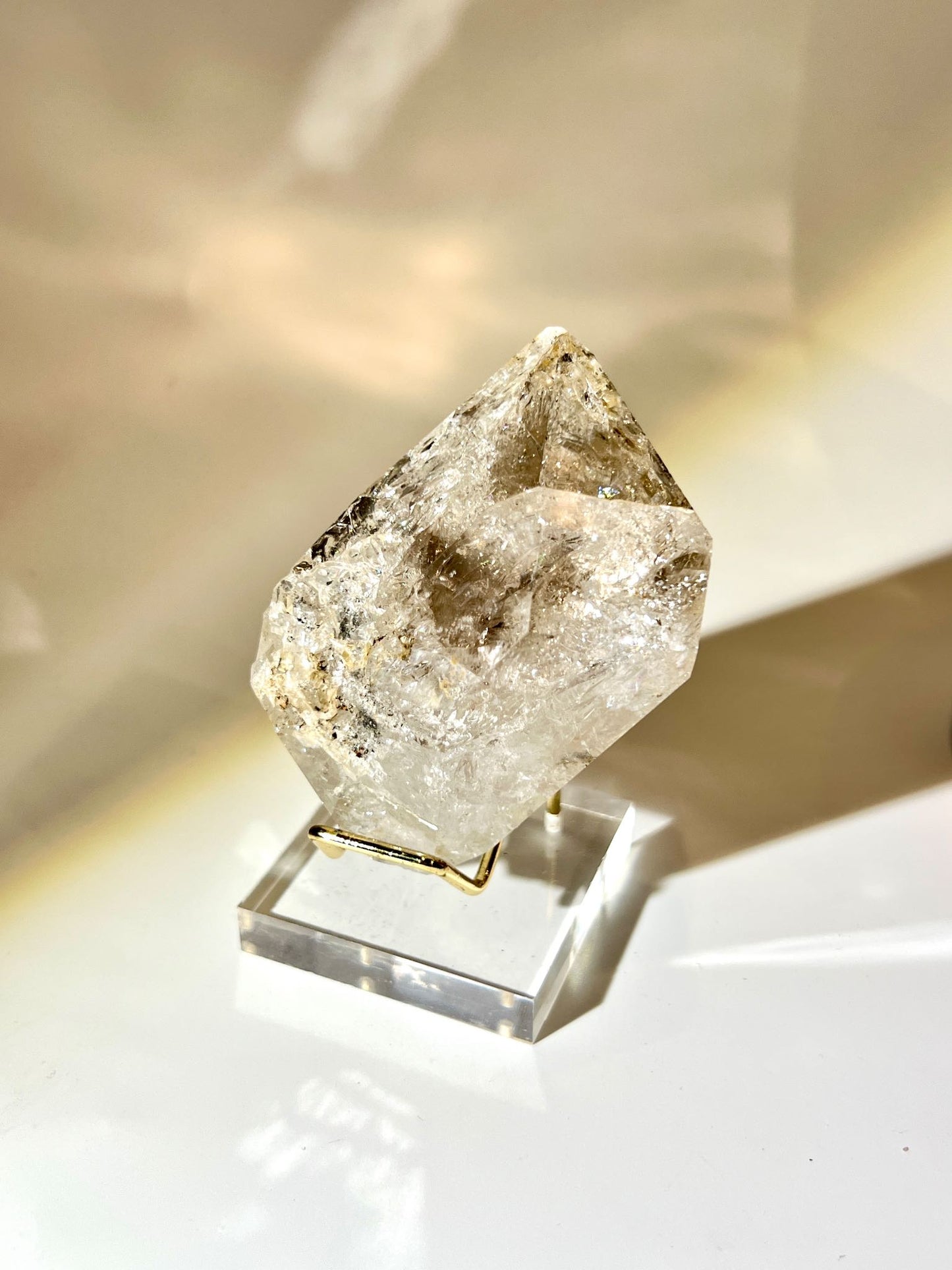 Large raw Herkimer Diamond crystal with strong rainbow reflections and thick-body formation held in hand.