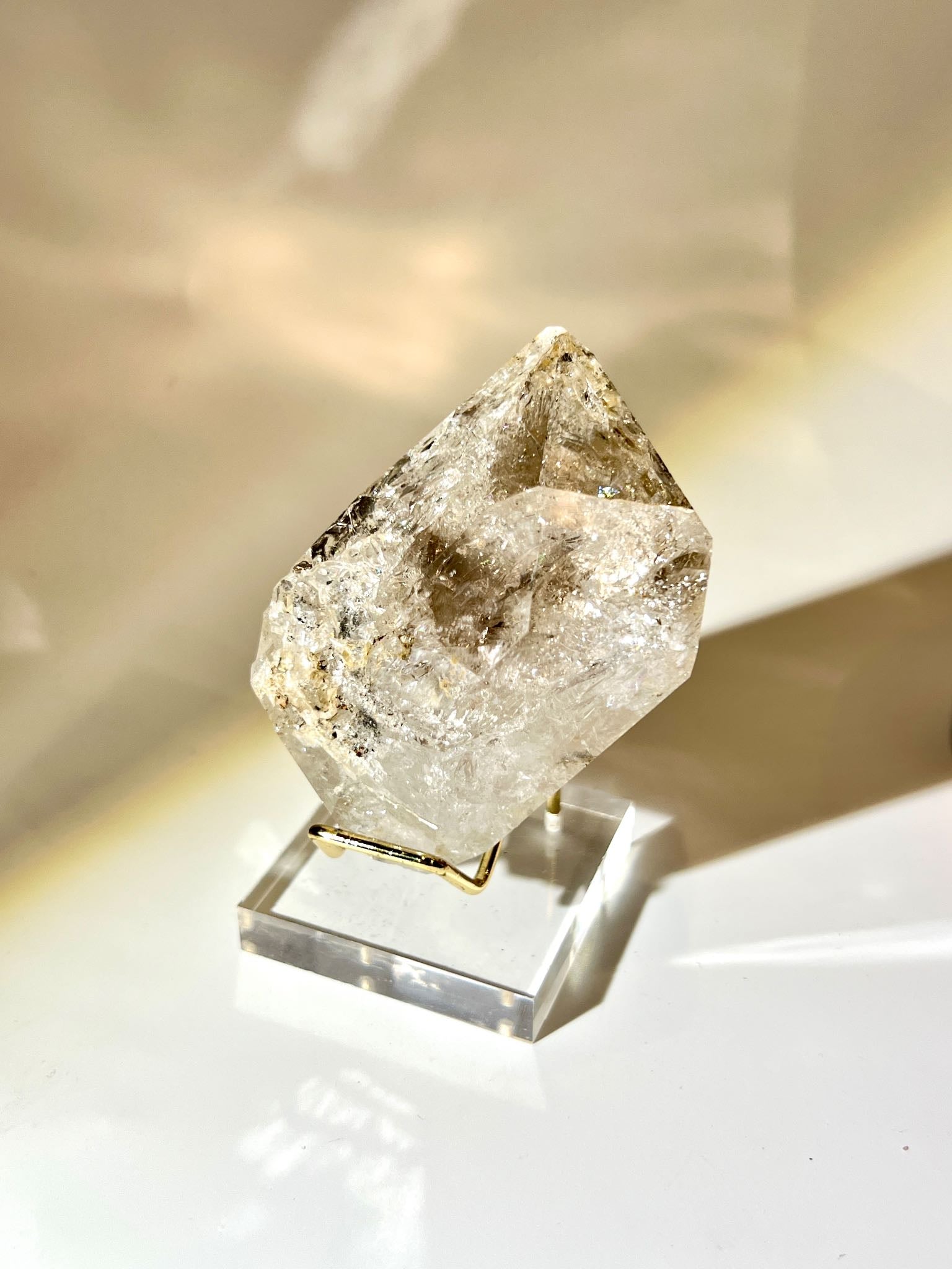 Large raw Herkimer Diamond crystal with strong rainbow reflections and thick-body formation held in hand.