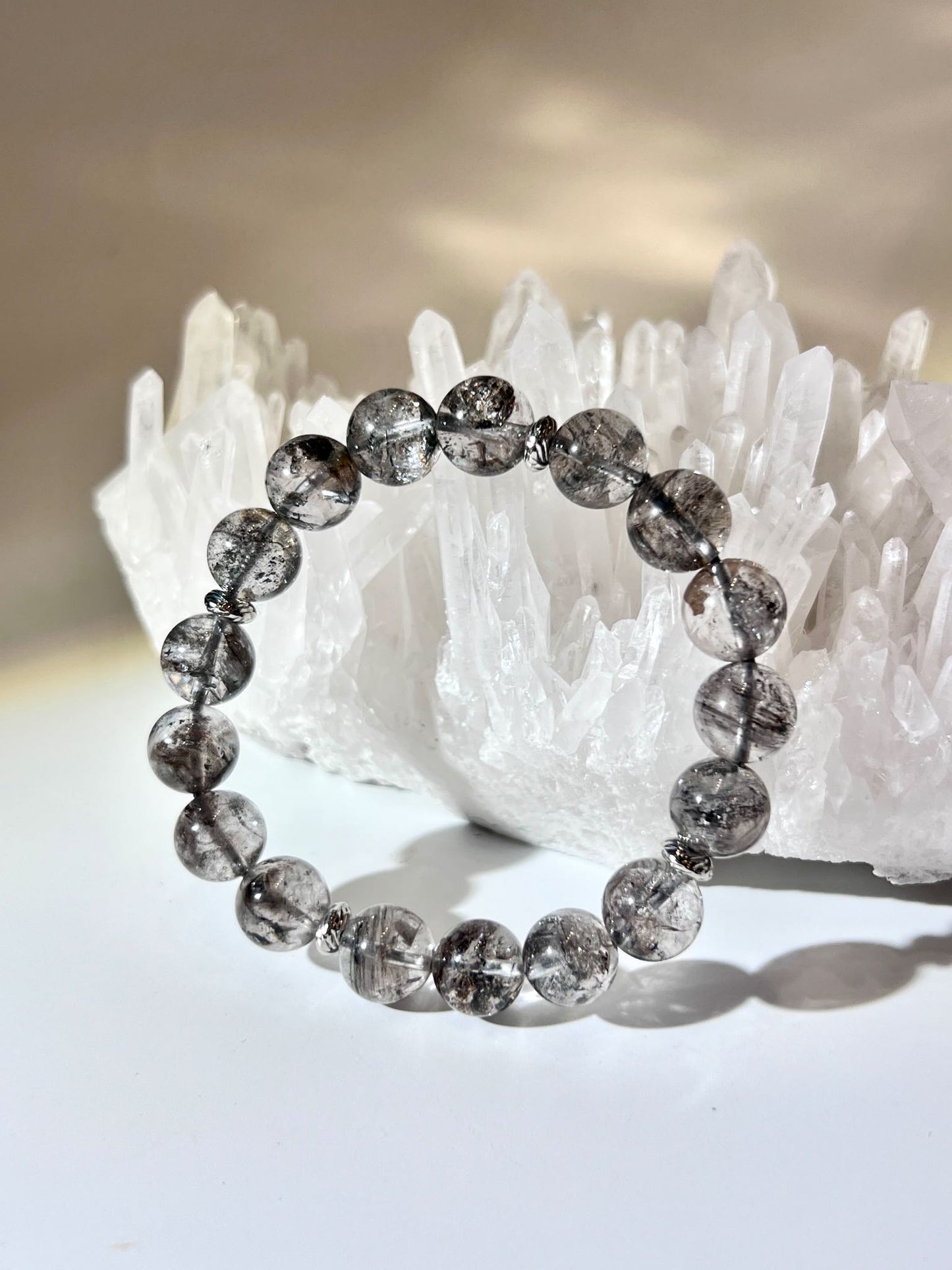 閃靈鑽手鏈 10.8MM 在白水晶簇前展示強勁內含物與透明度