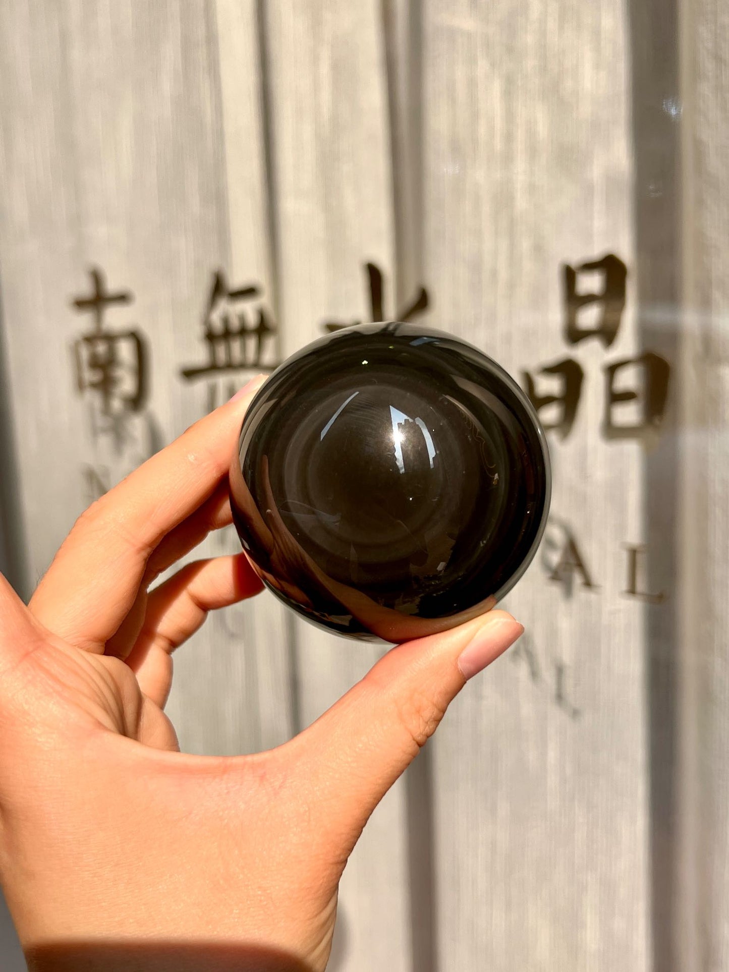 Hand holding obsidian sphere with central glowing sheen