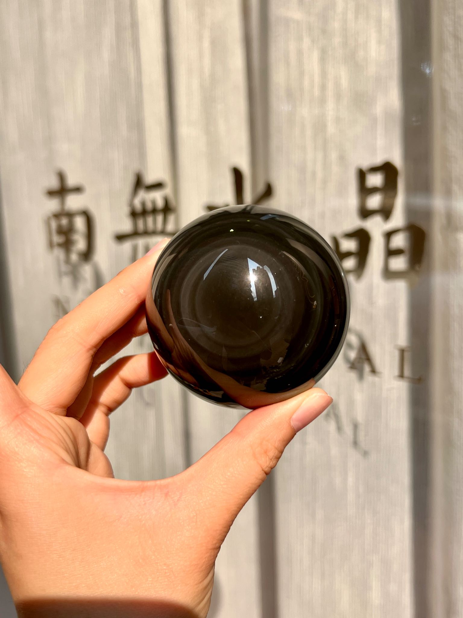Hand holding obsidian sphere with central glowing sheen
