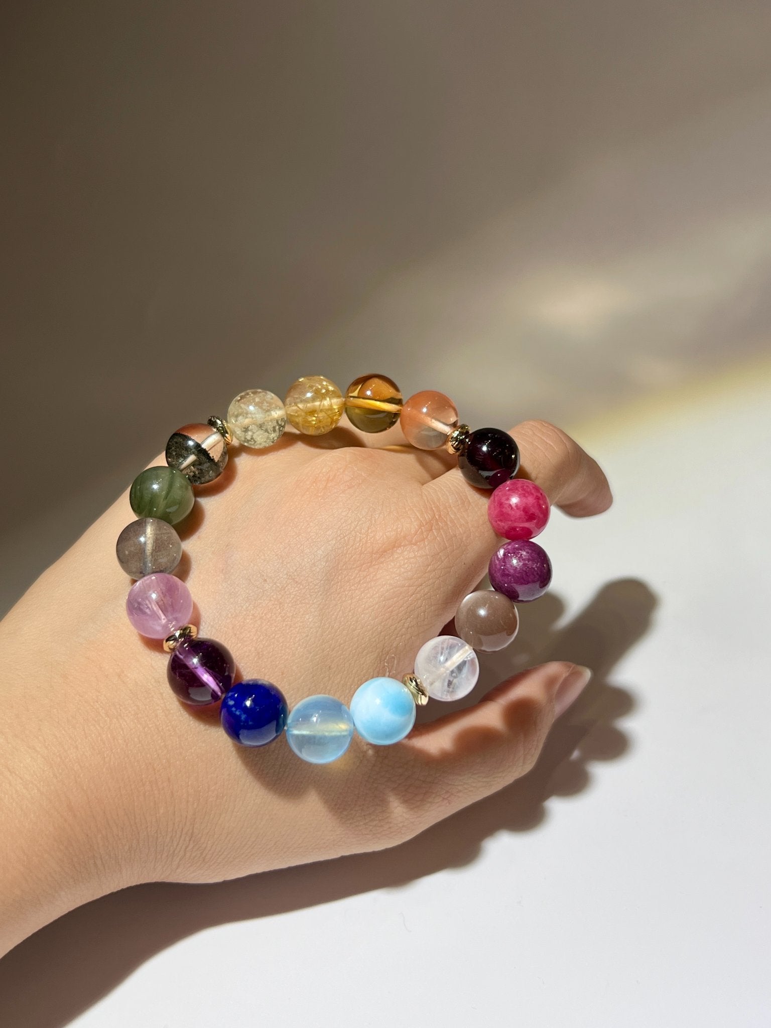 七脈輪水晶手鏈近拍圖，展示黃晶、海藍寶、青金石、紫超七及綠幽靈等天然晶石紋理